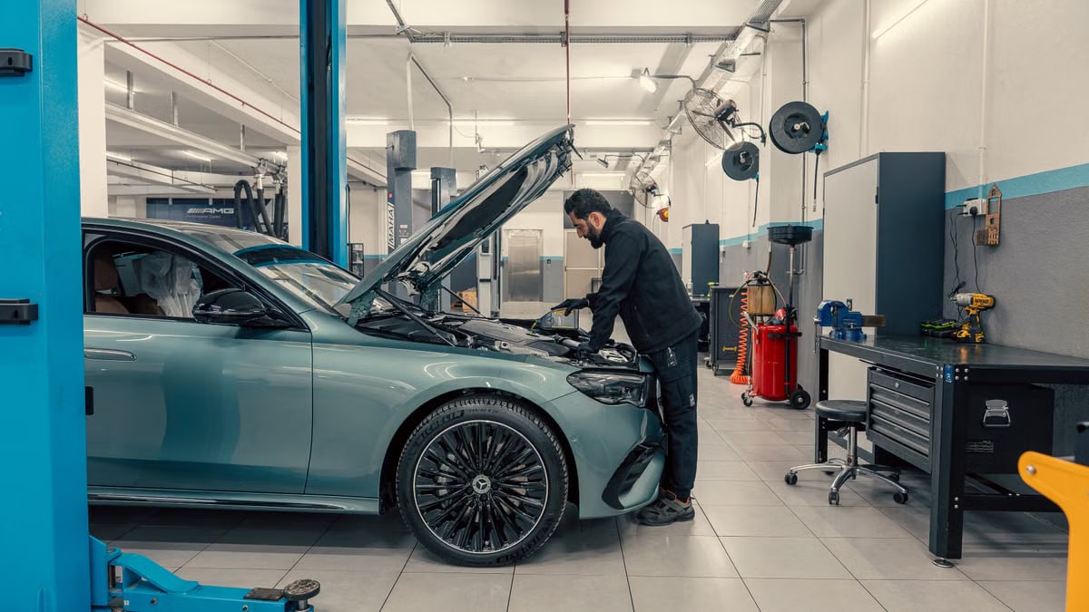 Mechanic inspecting a luxury car inside a well-equipped garage. Vehicle maintenance setting.